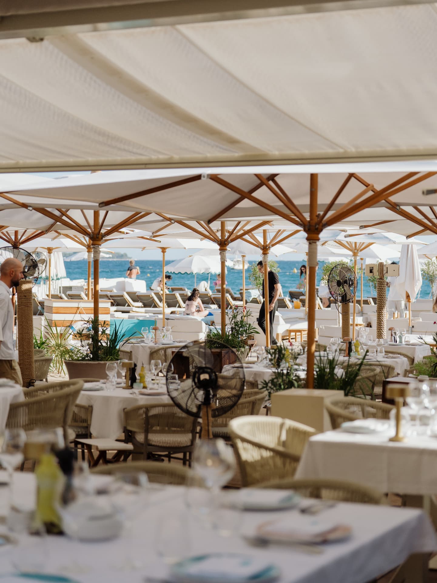 Tables set under parasols facing the sea