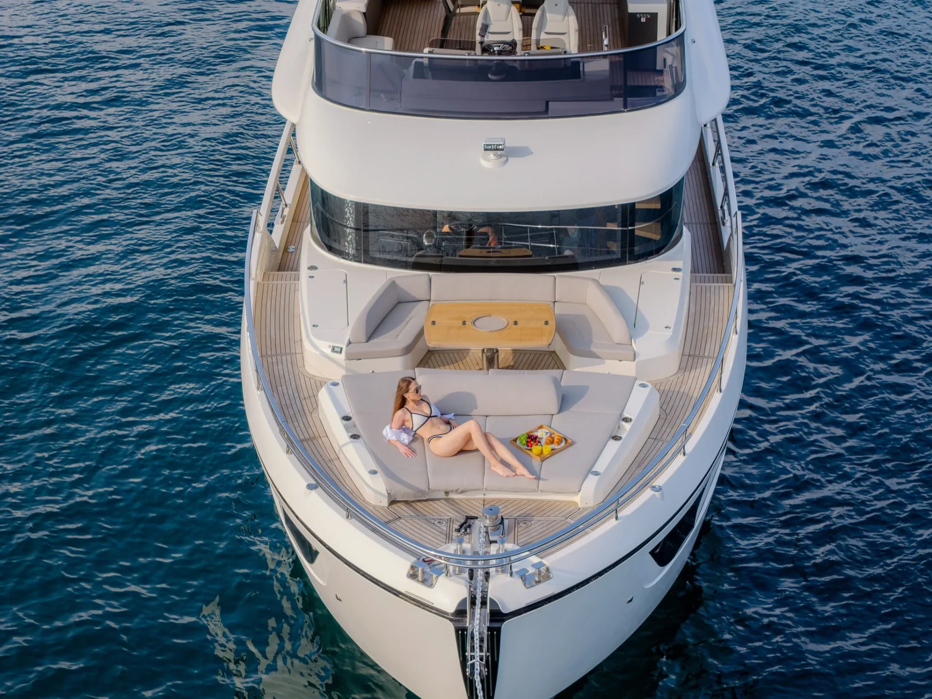 Guest lounging on the bow sunpad of a white yacht