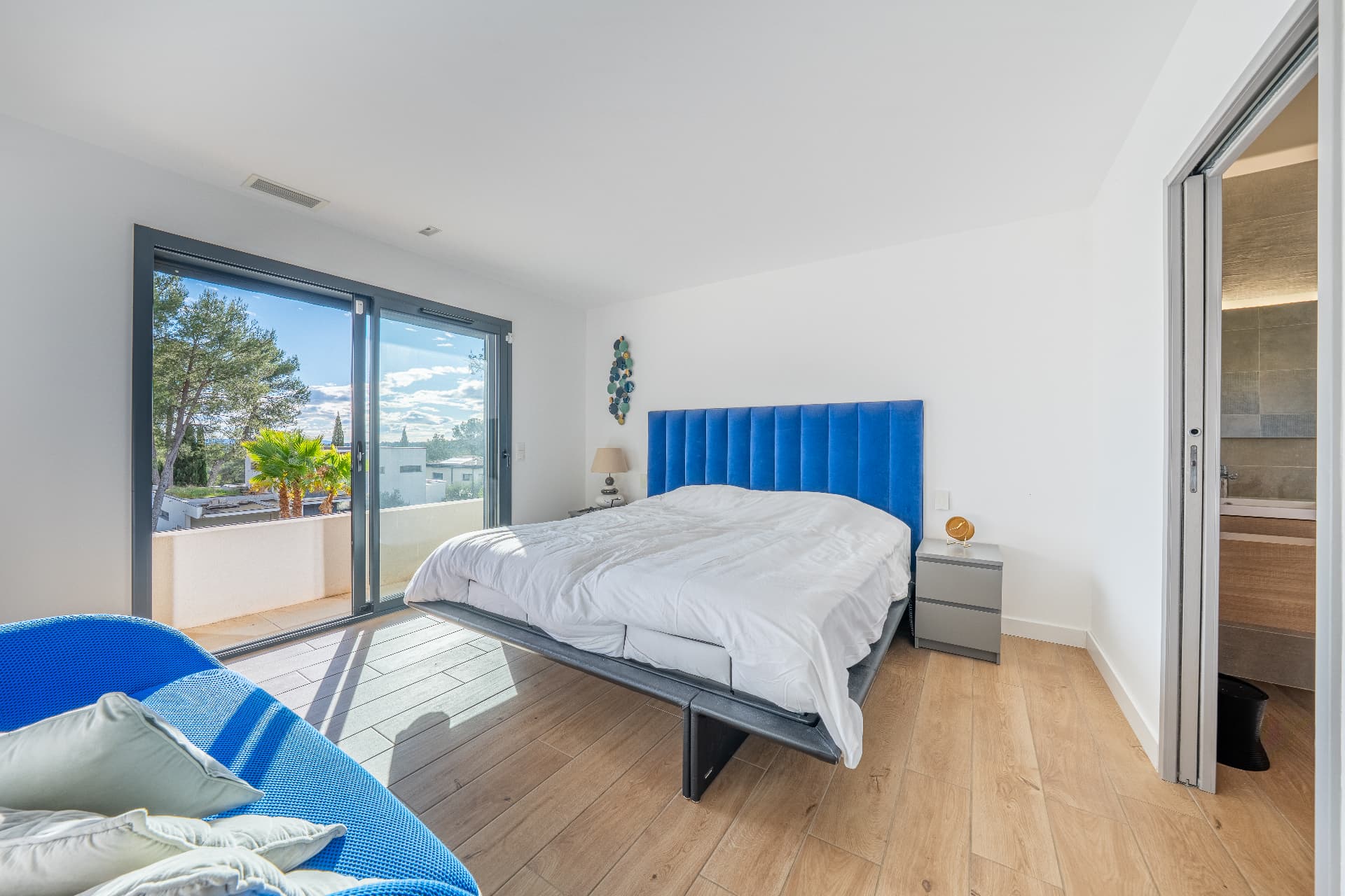 Bedroom with blue velvet headboard and balcony doors